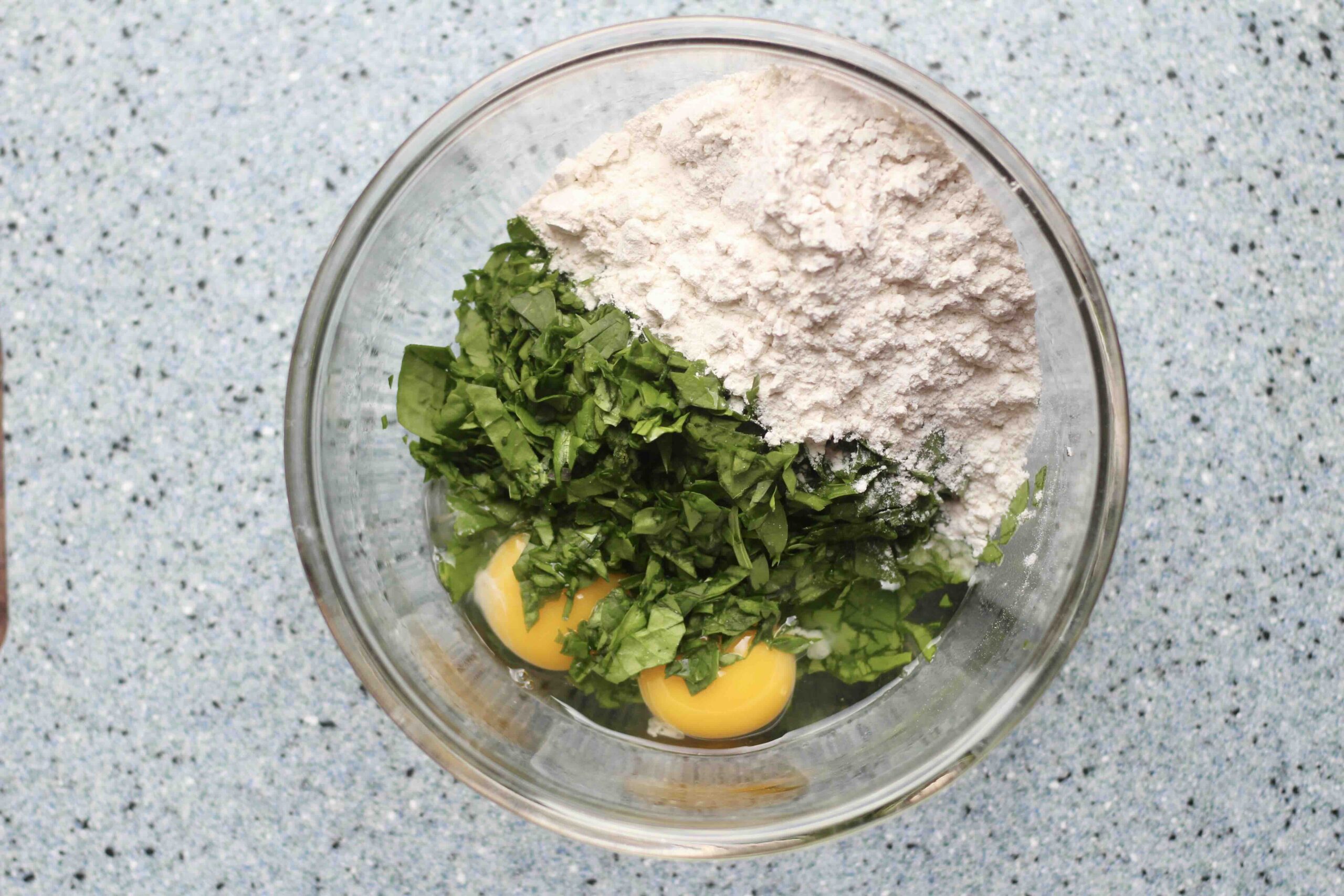 spinach, eggs, and flour in a bowl